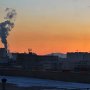 Furnaces roar to life at dawn amidst a backdrop of construction cranes.